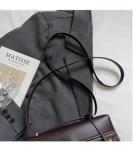 Detail of dark brown leather handbag featuring smooth texture and golden metal hardware buckles
