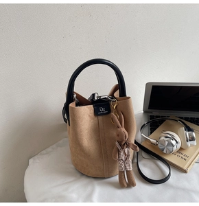 Close-up of brown suede bucket bag with black leather handle and a cute rabbit charm