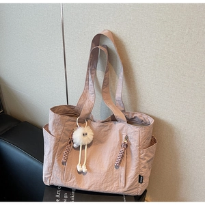 Detail of pink nylon tote bag showing side pockets and a cute plush doll charm