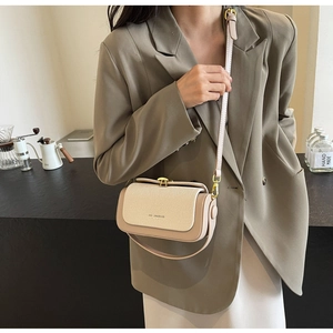 Dettaglio di una borsa a tracolla chic bicolore crema e beige con chiusura dorata