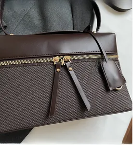 Detail of smooth gold dual zippers and V-shaped woven texture on a dark brown handbag
