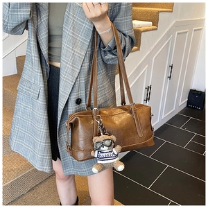 Vista dettagliata di una borsa a spalla vintage marrone con un ciondolo a forma di orsetto