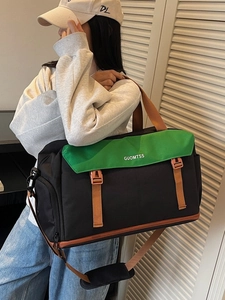 Large travel duffel bag in green and black canvas with adjustable shoulder strap and handles