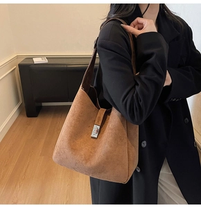 Close-up of brown suede bucket bag featuring a sleek silver metal buckle and large capacity