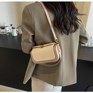 Dettaglio di una borsa a tracolla beige testurizzata con chiusura dorata e cinturino