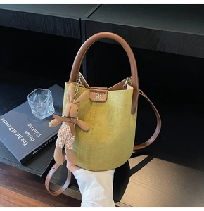 Detail of green suede bucket bag with leather handle and cute rabbit plush charm