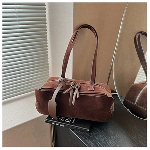 Close-up of vintage brown suede pillow bag with dual zippers and leather tags