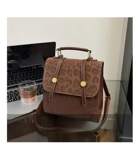 Detail der Handtasche mit Leopardenmuster und Goldknöpfen neben einem Laptop