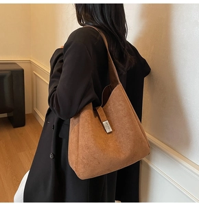 Detail of caramel suede tote bag featuring vertical metal buckle and soft texture
