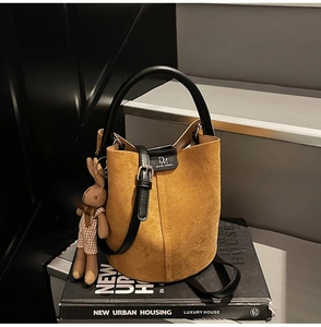Close-up of frosted suede bucket bag with leather strap and cute rabbit pendant detail