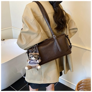 Dettaglio della borsa Boston vintage in ecopelle marrone scuro con ciondolo a orso