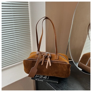 Detail view of brown matte suede pillow bag with leather tassel and silver zipper