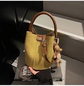 Detail of green frosted bucket bag with metal clasp and brown leather handle
