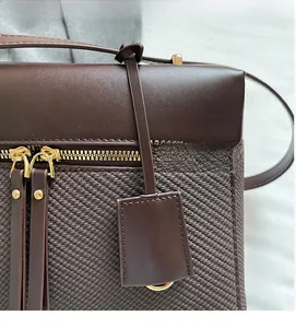 Detail of dark brown leather handbag with woven texture and gold zipper closure