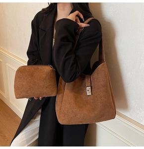 Detail view of brown matte bucket bag set with suede texture and metal buckle on a model