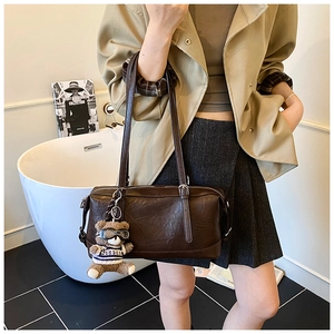 Dettaglio borsa a bauletto marrone retrò con ciondolo a forma di orso in un set chic