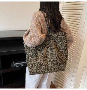 Close-up of a large leopard print canvas tote bag with black slim handles for women