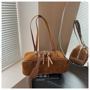 Detail of vintage brown suede pillow bag with dual straps on a wooden table