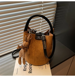 Close-up of brown suede bucket bag with black leather handle and a cute rabbit charm