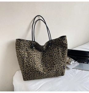Close-up of leopard print canvas tote bag with black leather straps and metal hardware