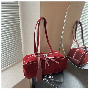 Macro shot of burgundy frosted suede shoulder bag with dual zippers and leather hangtag