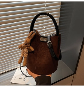 Detail of matte dark brown bucket bag with knit bunny pendant and circular handle