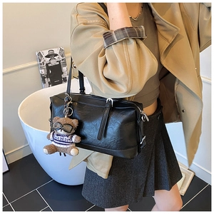 Dettaglio di una borsa bowling in pelle nera con un simpatico portachiavi a forma di orsetto