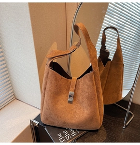 Mirror reflection showing details of a vintage brown suede bucket bag with a metal buckle