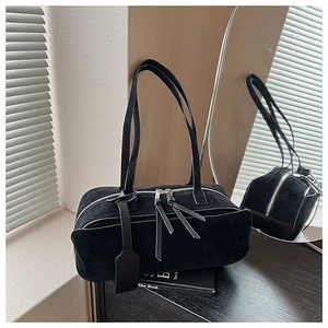 Detailed macro view of black matte suede shoulder bag with dual silver zippers and tassels