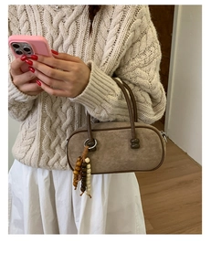 Dettaglio di borsa Boston vintage in pelle scamosciata marrone con nappa in legno e manico