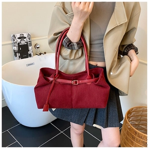 Detalle del bolso tote de pana roja mostrando la textura gruesa y la hebilla de cuero
