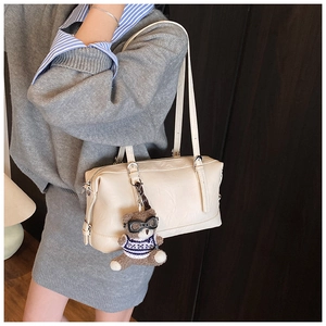 Dettaglio della borsa Boston beige in morbida pelle con un grazioso ciondolo a orsetto