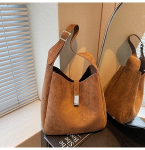 Detail of dark brown suede bucket bag featuring a silver metal buckle and soft matte texture