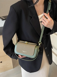 Borsa a tracolla verde e beige indossata da una modella in uno stile completo elegante