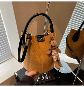 Detail of suede bucket bag with round handles and a cute rabbit charm pendant
