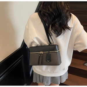 Detail view of stylish color-block handbag with zipper closure and houndstooth pattern