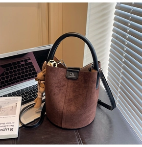 Detail of dark brown suede bucket bag featuring a black round handle and a cute rabbit charm