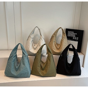 Détail de grands sacs à bandoulière décontractés en cinq coloris sur des escaliers