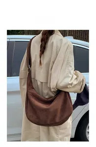 Vue détaillée de dos d'un modèle portant un grand sac hobo en daim marron mat en ville