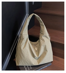 Détail du sac fourre-tout en nylon vert sauge avec texture froissée sur escalier