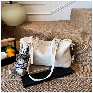 Dettaglio di una borsa Boston in pelle bianco crema con fibbie argentate su una scala