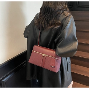 Detail view of reddish brown square handbag featuring woven leather texture and metal zipper