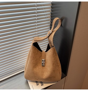 Detail of brown matte bucket bag showing the silver metal buckle and wide strap design