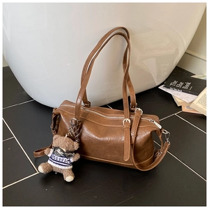 Dettaglio borsa bowling vintage in pelle marrone con ciondolo a orsetto e zip in metallo