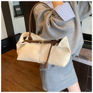 Detail of off-white corduroy tote bag with brown leather straps and metal buckle