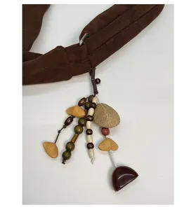 Gros plan d'un pendentif ethnique avec perles en bois et cloches sur sac en daim brun
