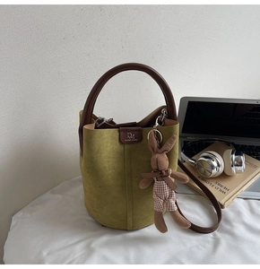 Detail of green frosted bucket bag with leather logo handle and cute rabbit charm