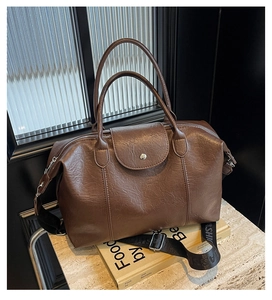 Close-up of a retro brown boston bag with lychee texture and metallic snap buckle detail