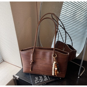 Close-up of brown woven tote bag with wooden bead charm and elegant textured finish