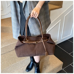 Detail view of dark brown corduroy tote bag with leather straps on indoor stairs